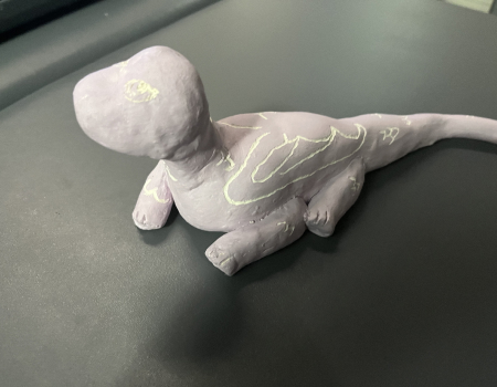 An image of Lilia's ceramics project. It is a purple dragon with wings etched into it made out of clay