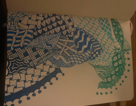 An image of Lilia's zentangles. They are complex, zen style patterns all over the page in various shades of blue